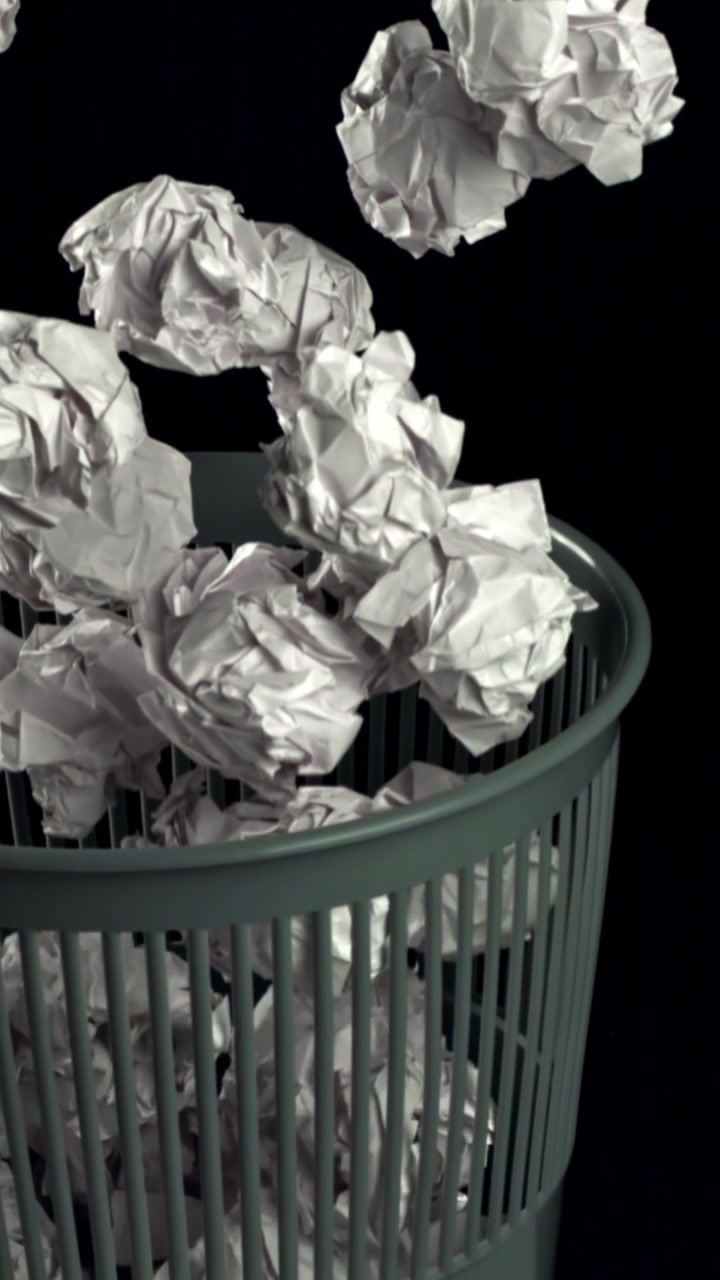 Palline di carta accartocciate che cadono in un cestino dei rifiuti