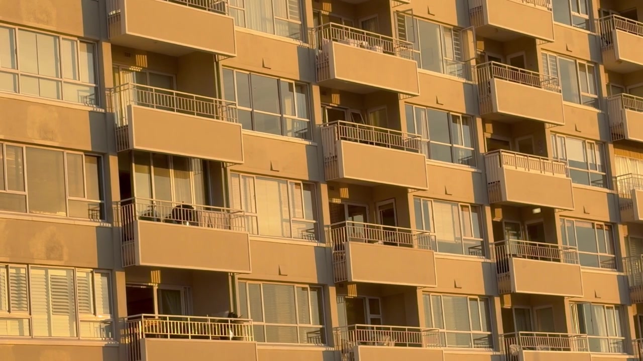 Um edifício de apartamentos com o sol do fim da tarde sobre ele.