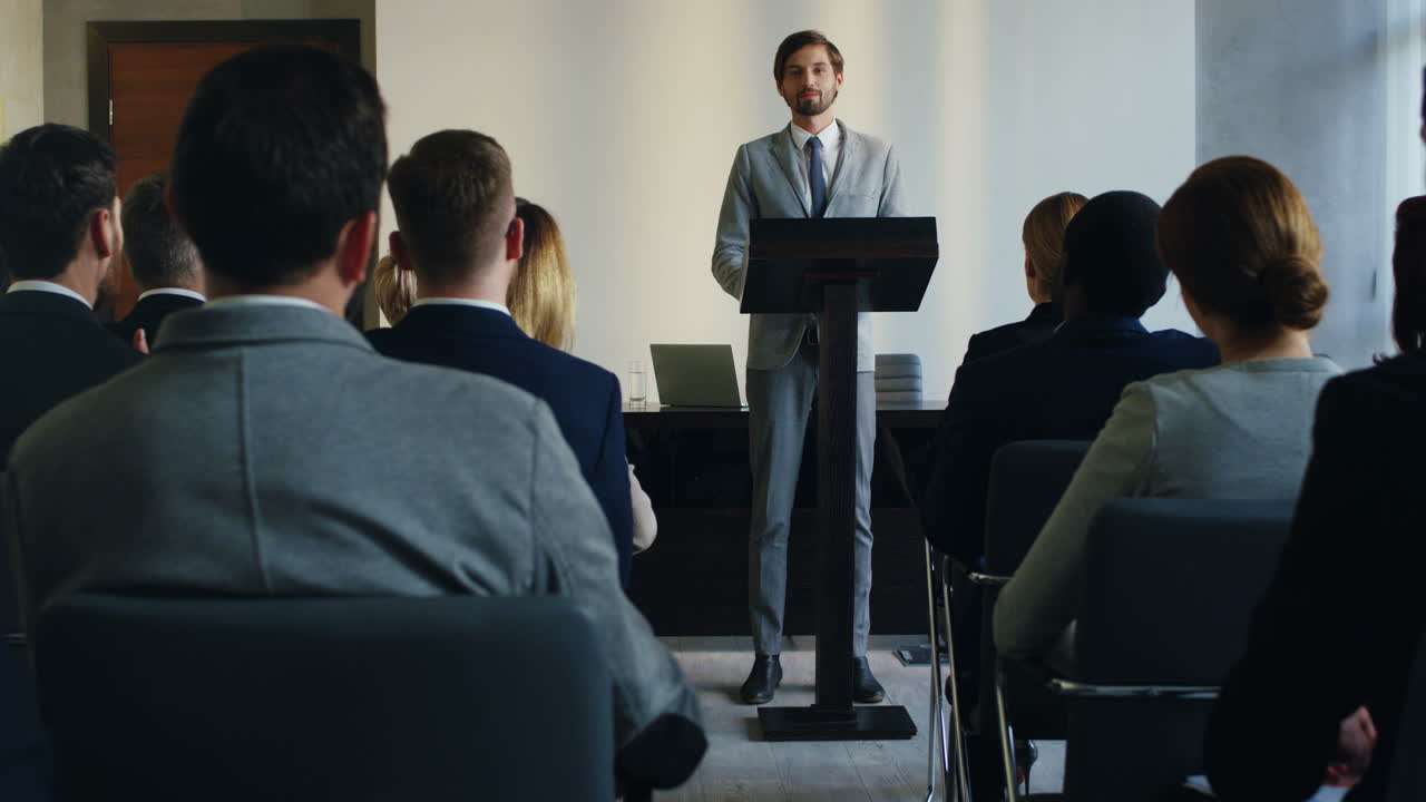 Caucasian businessman on a podium at a conference and answering question to the people in the hall during his speech