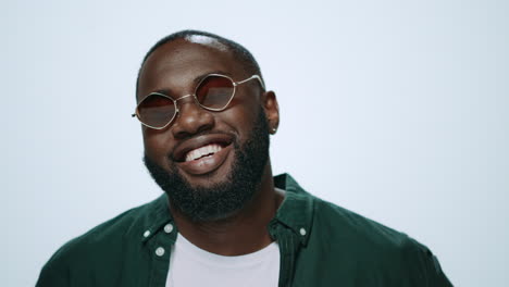 Closeup-happy-african-man-smiling-in-sunglasses-on-camera-in-grey-background.