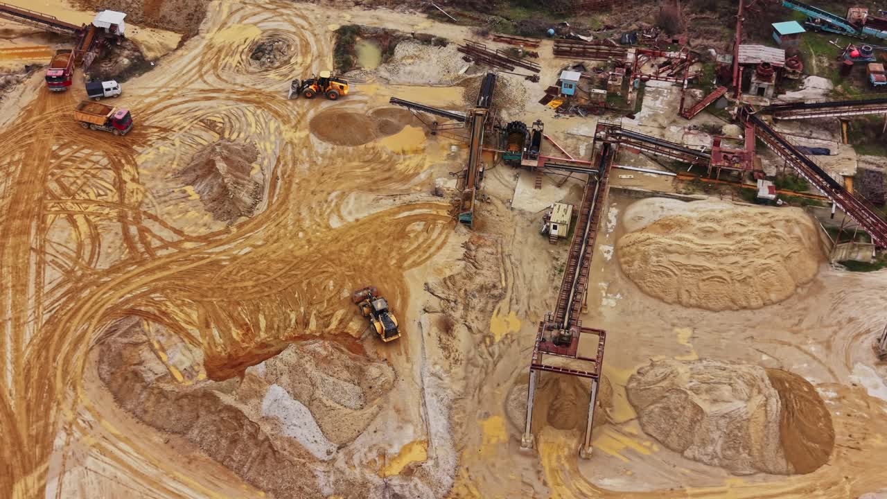 Sand extraction process at quarry site during daytime with machinery