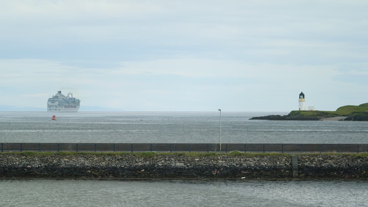 Static shot of a cruise ship leaving port and a lighthouse in Stornoway