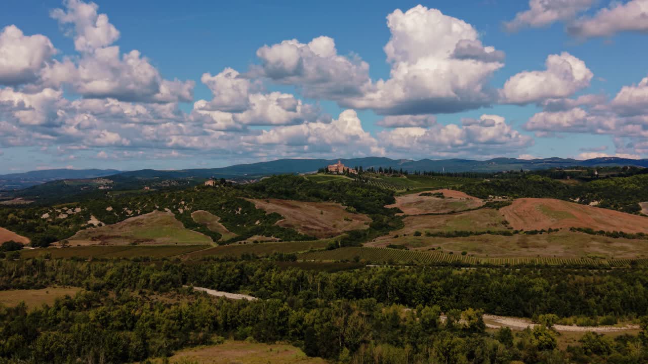 Tuscany landscape near Grosseto with vineyard fields, olive trees and hills with historic village