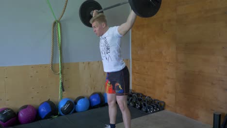 man performing a weightlifting exercise in a gym