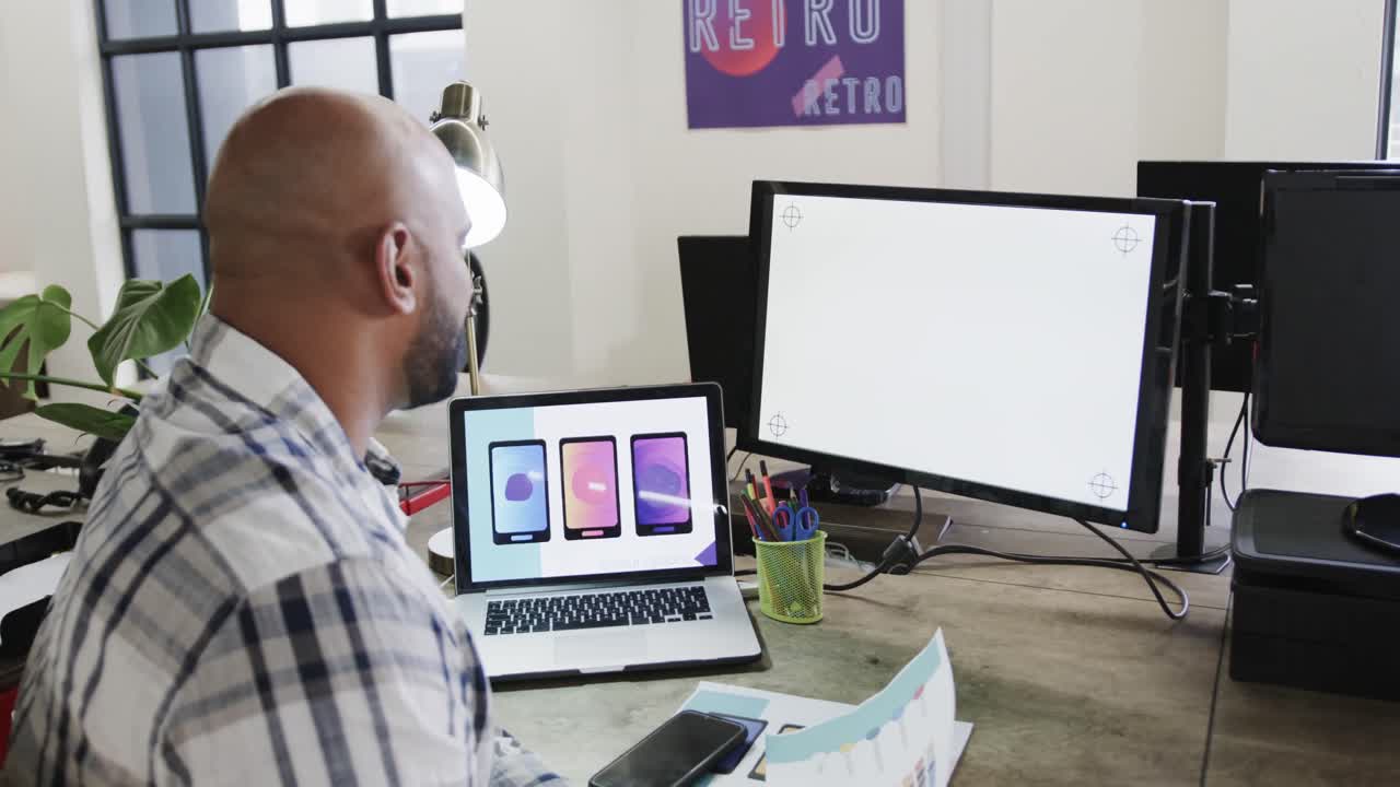 diseñador masculino biracial usando computadoras con espacio de copia en una oficina casual, cámara lenta
