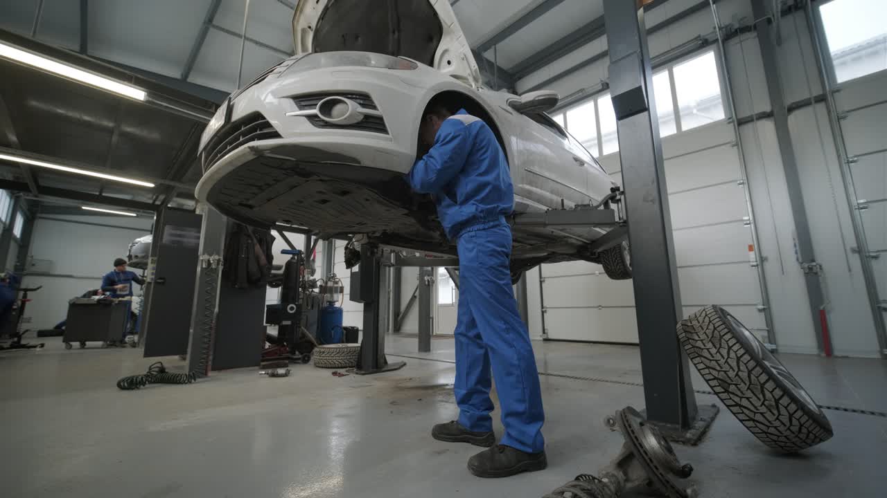 mecánico de automóviles reemplazando las patas de freno de la rueda del automóvil levantado en la estación de servicio de reparación