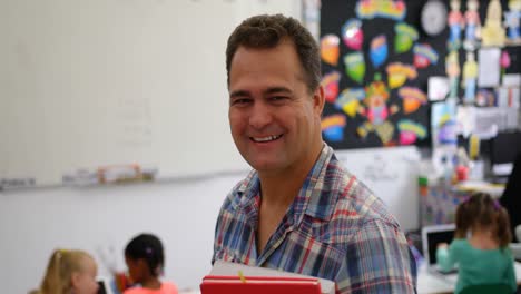 Front-view-of-Caucasian-male-teacher-holding-books-in-the-classroom-4k