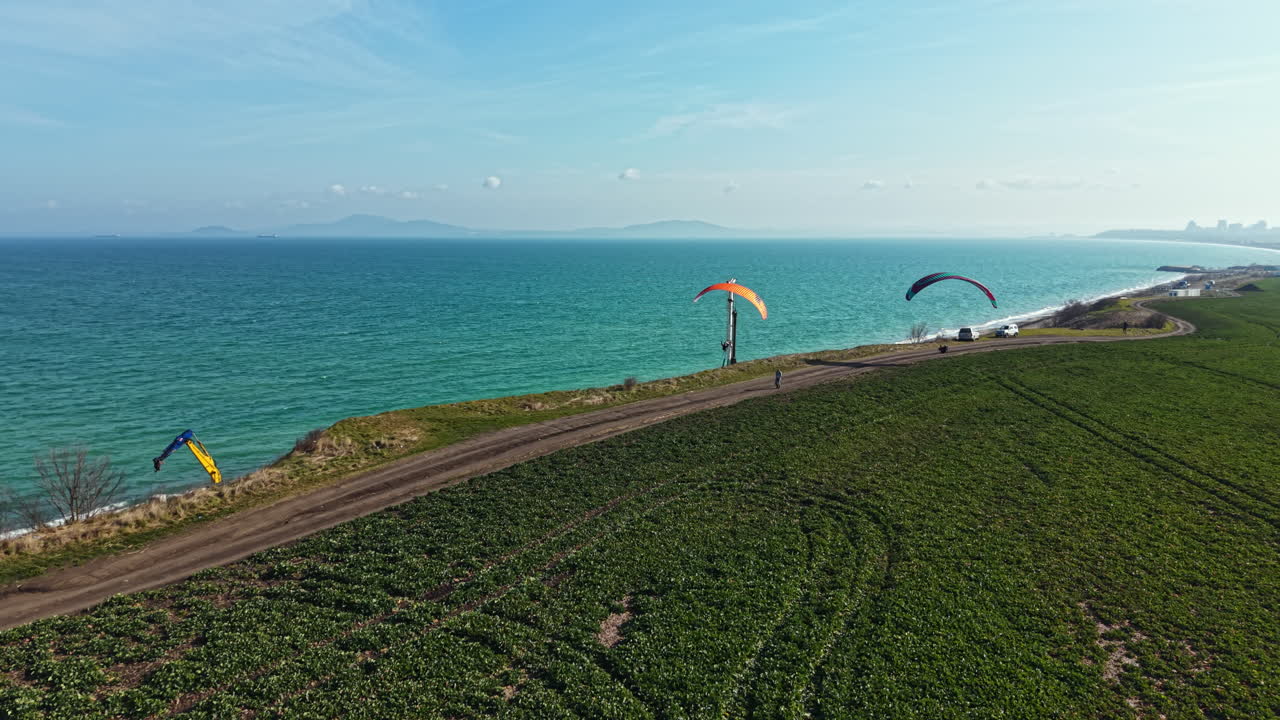 Parapente sobre o oceano com um canteiro de obras próximo na praia sob a luz da tarde.