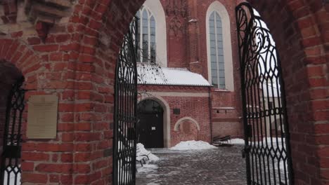 dolly in shot of a red brick church courtyard passing through gate walking forward