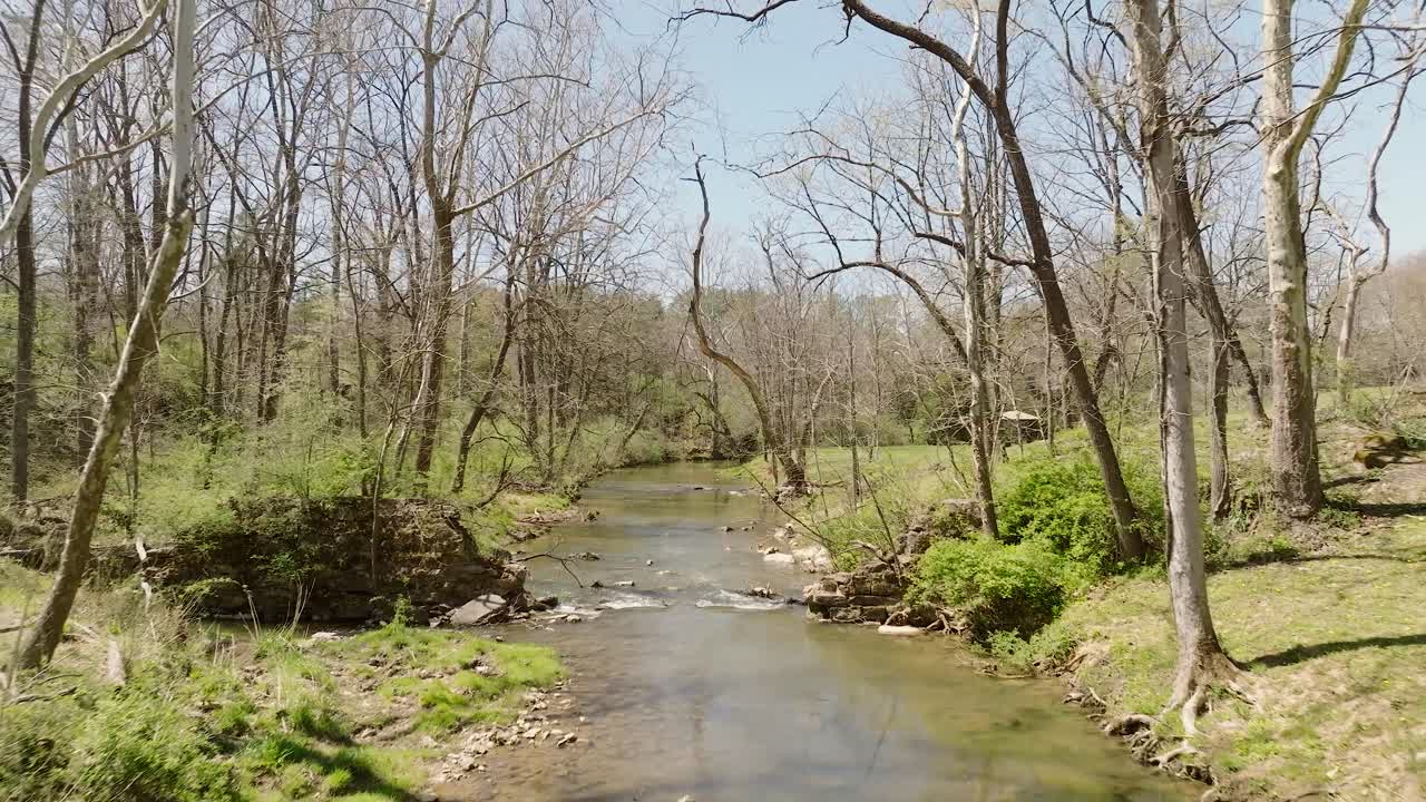 vista aérea de un arroyo natural que fluye en primavera con agua en movimiento a través de los árboles en cámara lenta