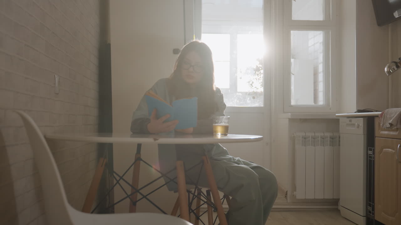 Una lettrice si gode una tranquilla mattinata in una cucina accogliente. Scena delicata di una donna che scrive in un'atmosfera domestica calda. Donna tranquilla che scrive un diario in una cucina illuminata dal sole con arredi minimali e illuminazione soffusa.