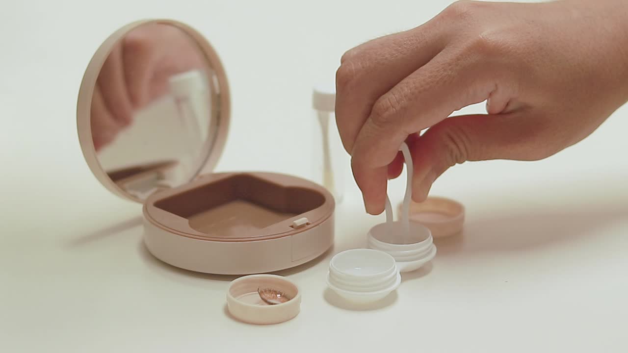 Hand struggling to pick up contact lens using plastic tweezers showing the hardship, hygiene and routine of eye care