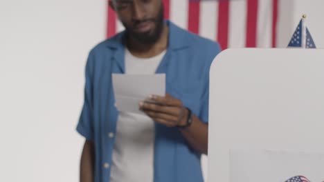 confused man stands at ballot box in american election deciding how to cast his vote