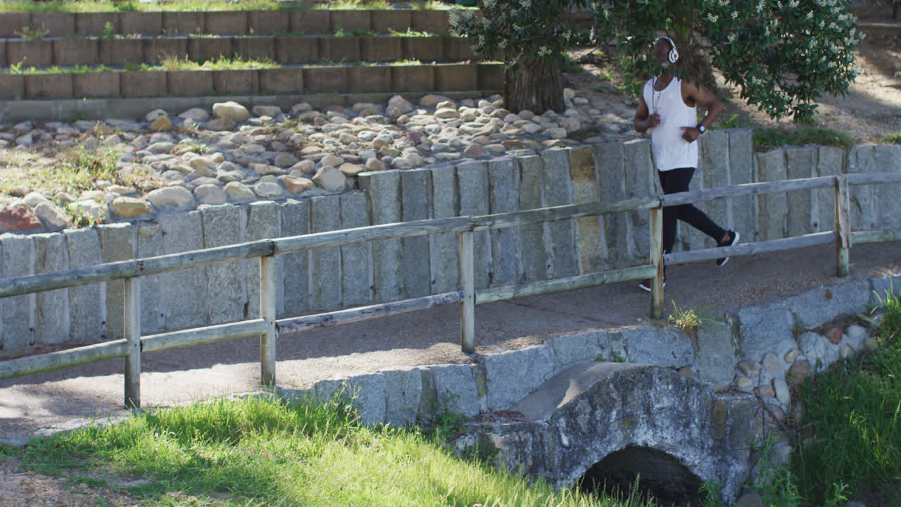 시니어 아프리카계 미국인 남자가 바 ⁇ 가의 도로에서 달리기를 연습하고 있습니다.