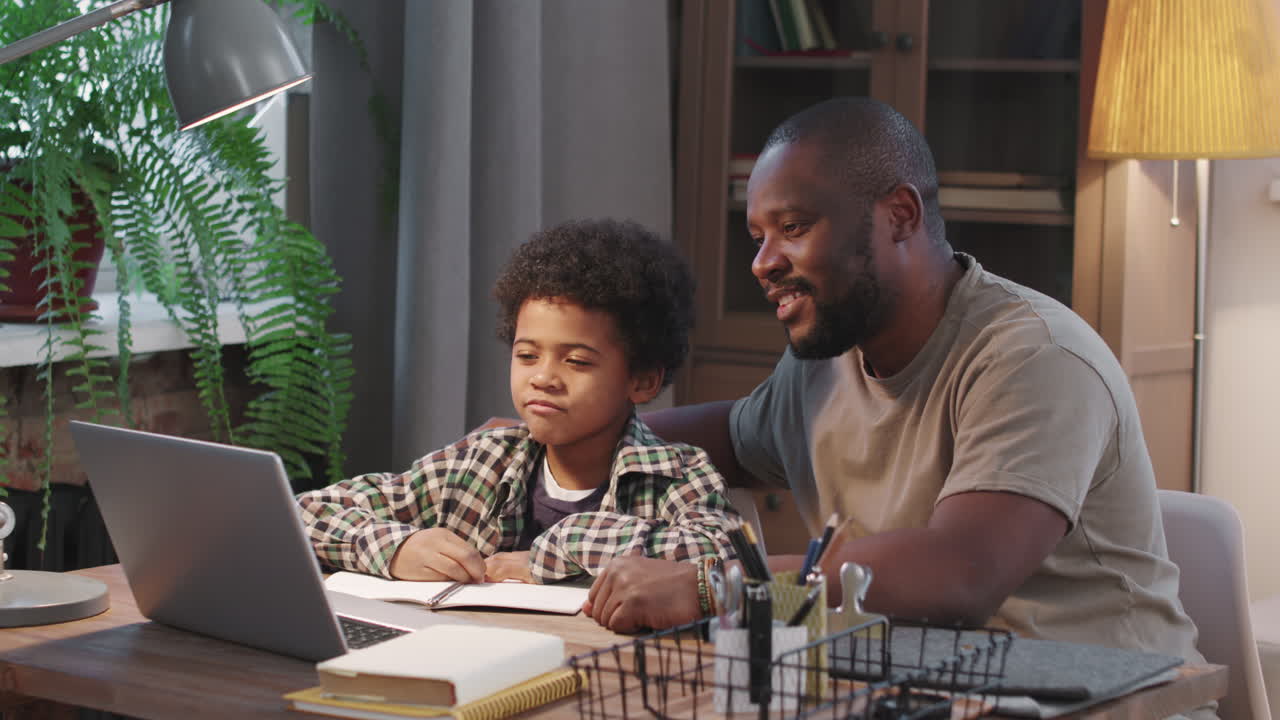 Padre afroamericano e figlio che salutano l'insegnante online
