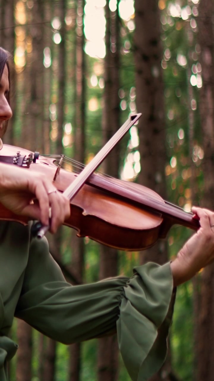 Người phụ nữ chơi violin trong khung cảnh rừng