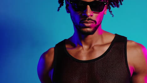 stylish man with dreadlocks and sunglasses in neon lighting