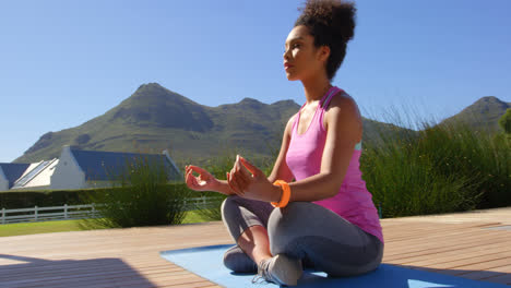 front view of young pretty mixed-race woman doing yoga in backyard of home 4k