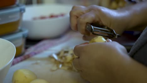 person peels a potato, symbolizing the process of food preparation, vegetable prep for cooking, and the promotion of a vegetarian diet and healthy eating habits