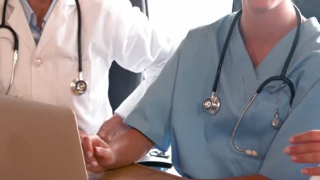 Doctors-talking-with-laptop-and-tablet-on-desk