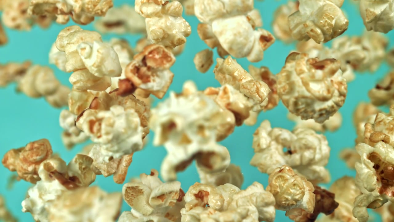 Popcorn Floating in Mid-Air Against a Teal Background