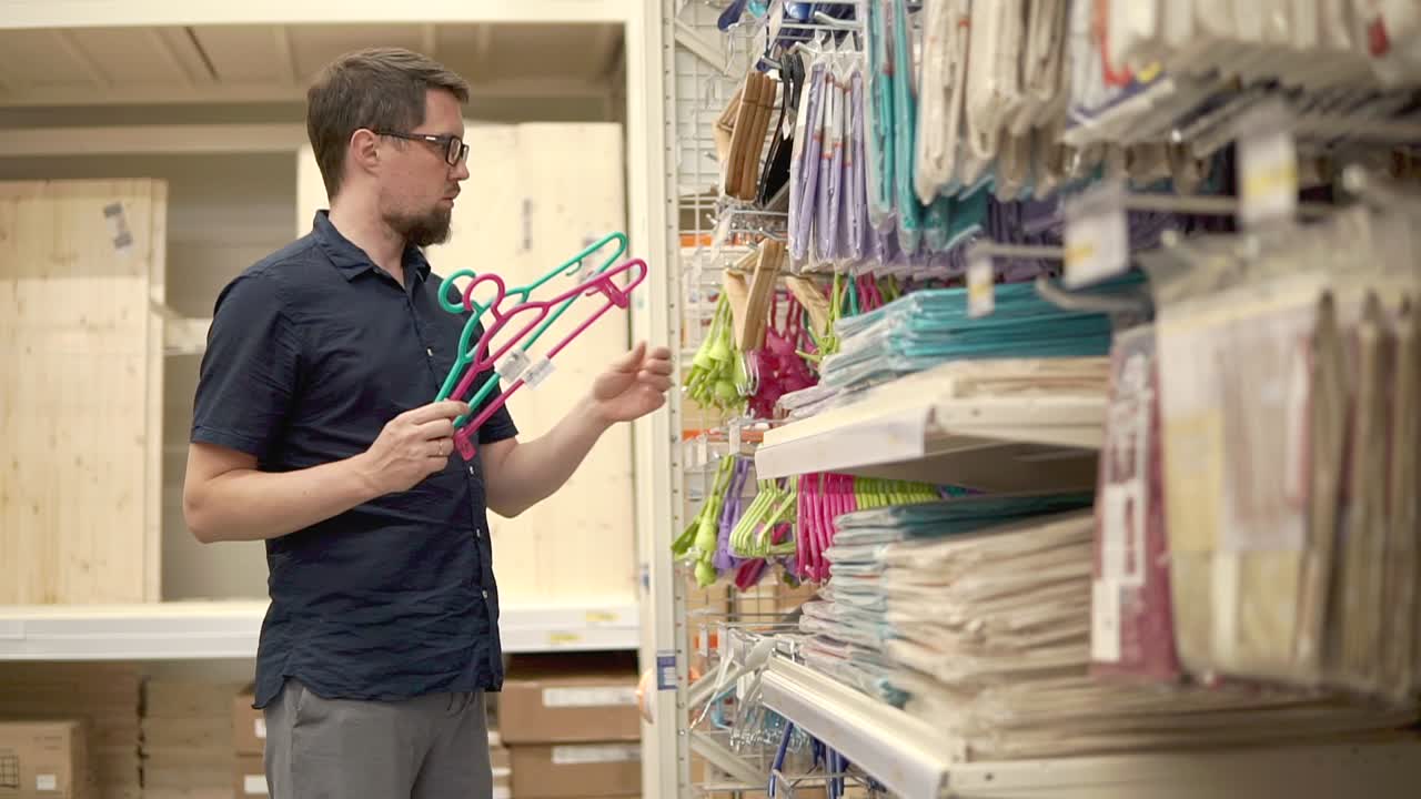 hombre comprando perchas de ropa en una tienda de artículos para el hogar