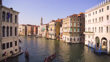 a lot of traffic and some typical gondolas on the famous canale grande, the main canal in venice, seen from the iconic rialto bridge