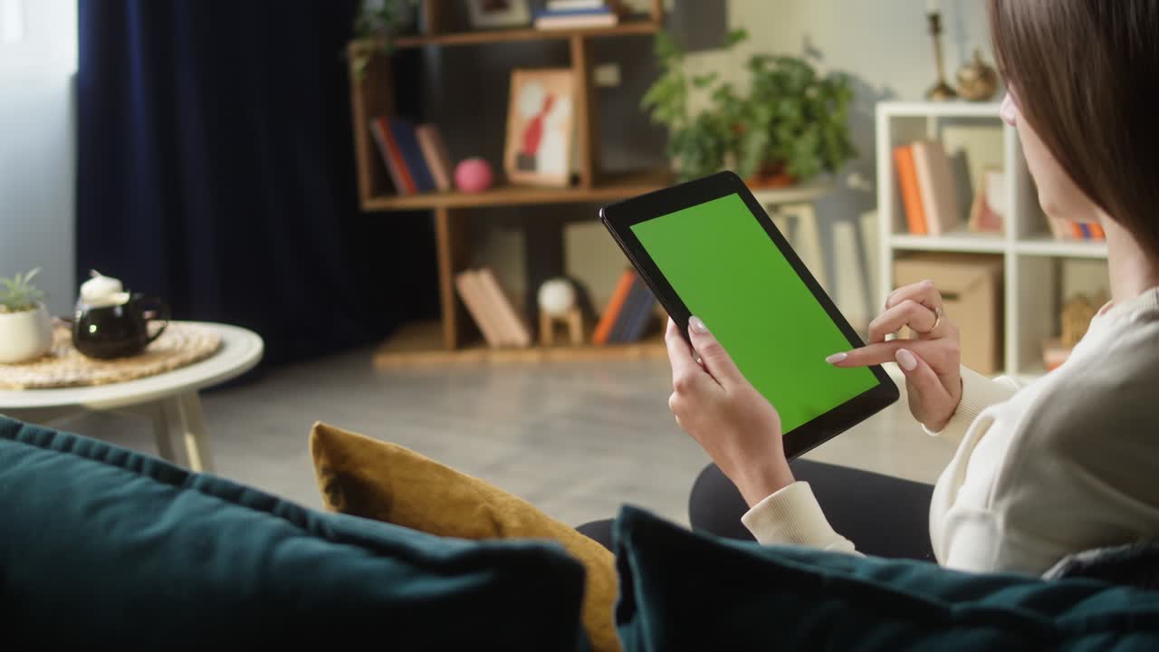 женщина, использующая гаджетный планшет с зеленым экраном. неузнаваемая женщина, пробирающаяся по клавише chroma, сидящая на диване в гостиной. онлайн-покупки, серфинг в интернете. свободное время дома, досуг