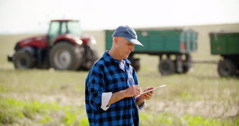 farmer using digital tablet while looking at tractor in farm 4