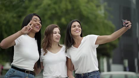 mujeres sonrientes posando para una selfie en la calle