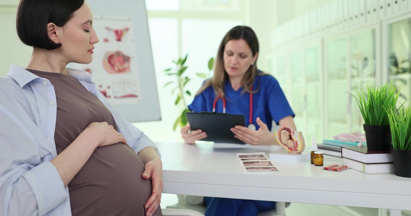 Pregnant woman signs patient consent with doctor in clinic office