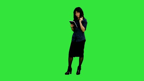 cheerful young asian woman with backpack have an idea and holding notebook on a green screen, chroma key