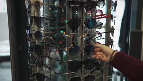 mujer eligiendo gafas de sol en una tienda minorista