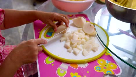 mujer corta manzana en trozos pequeños preparando ingredientes para hornear pastel de frutas
