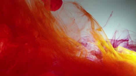 colorful cloud swirls of red and yellow acrylic dye ink falling slowly into water, prismatic multi color overload and very mesmerizing footage