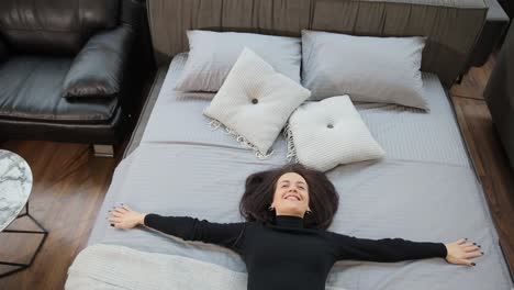 a woman tests beds at a furniture store to show bedding options a woman tests different beds in a furniture store sitting on one and then lying down with arms outstretched the video displays various bedding options at the store