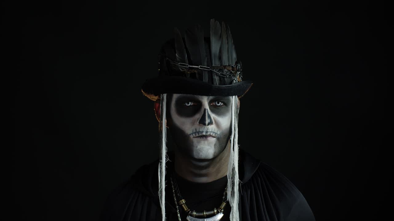 Uomo sinistro con trucco da scheletro di Halloween che gira la testa e guarda in camera, cercando di spaventare.