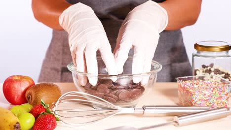 hands arranging chocolate discs in a bowl