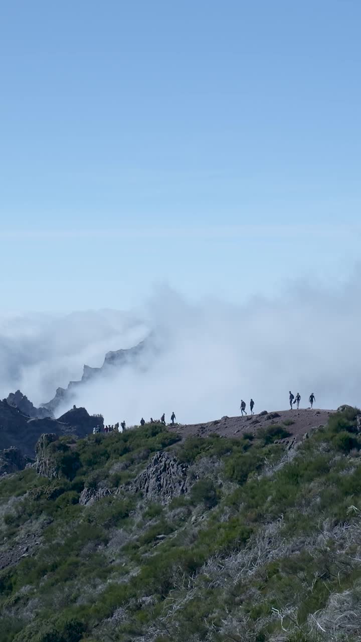 Hikers Walk Along Mountain Ridge Above a Sea of Clouds