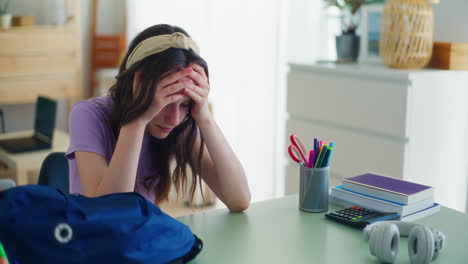 a sad young student breaks down after returning from school and sits sadly at her desk