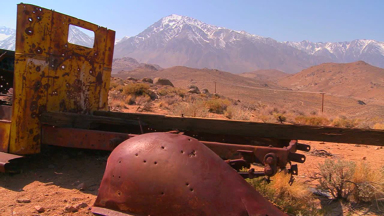 toma panorámica junto a una camioneta abandonada con las montañas nevadas de sierra nevada como telón de fondo