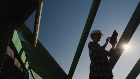 a young female architect exercises author's control at a construction site uses a tablet