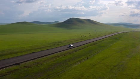 suv car driving an idyllic road of plateaus and steppe grasslands in mongolia