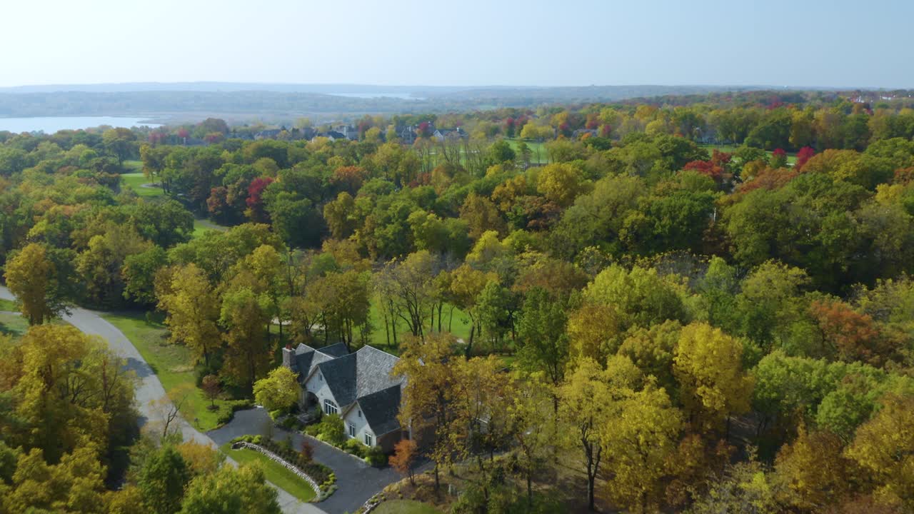 drone vuela sobre grandes casas rodeadas de paisaje otoñal en un campo de golf