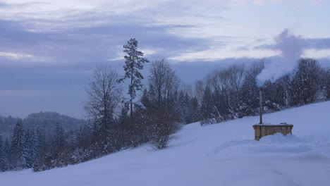 Smoking-furnace-at-dusk-in-winter-in-the-mountains,-Poland,-wide-shot