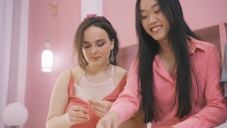 Bottom-View-Of--Friends-Making-Cardboard-Decorations-On-A-White-Table-For-Bachelorette-Party-Celebration