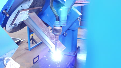 closeup, blue robotic welder welding peace of metal