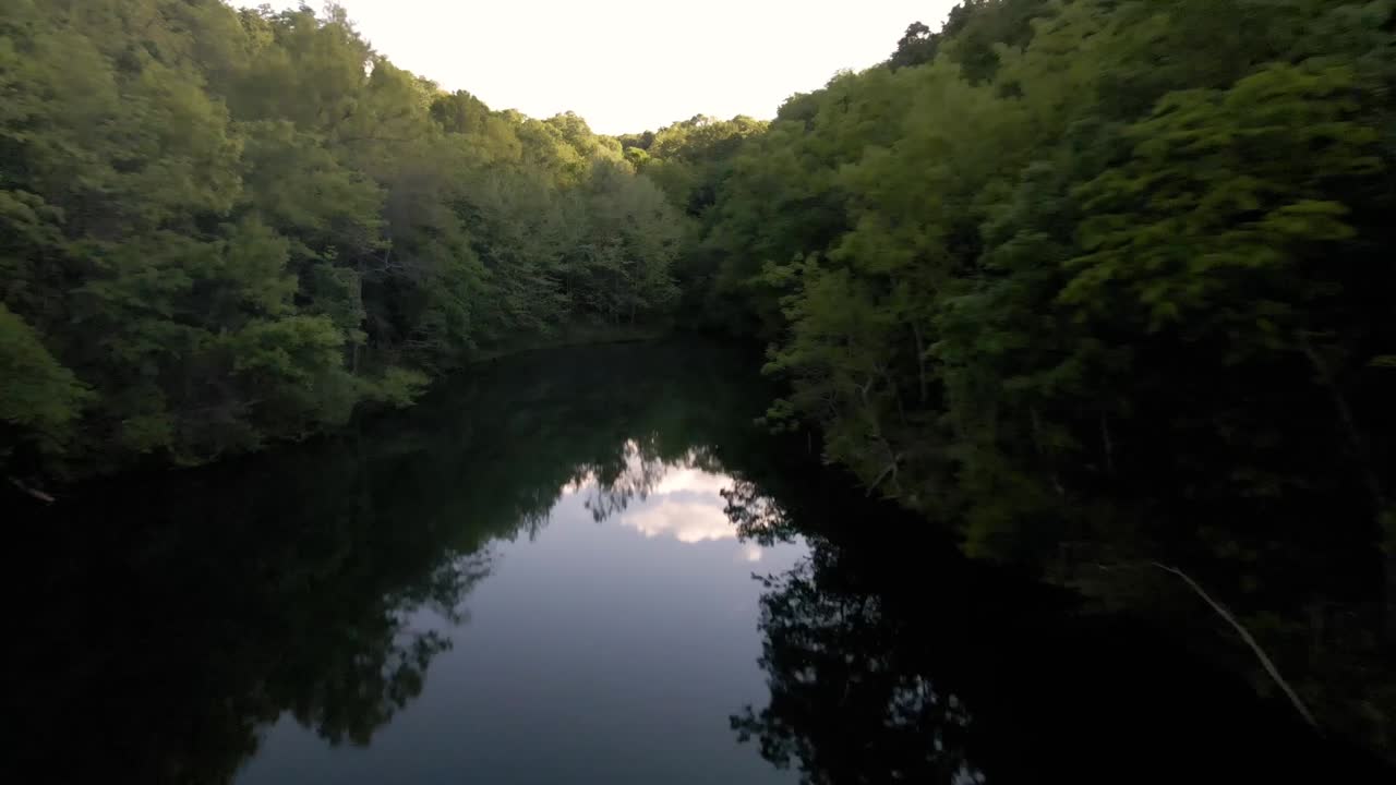 이것은 수많은 숲으로 둘러싸인 작은 오두막이 있는 개인 호수의 항공 사진입니다.