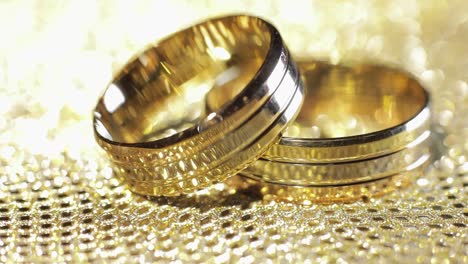 wedding gold rings lying on shiny glossy surface. shining with light. close-up