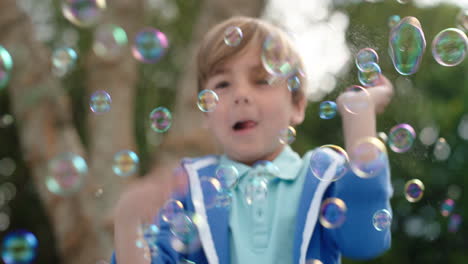 niño feliz atrapando juguetón burbujas de jabón flotando con un niño lindo divirtiéndose haciendo estallar burbujas en un parque soleado juego de la infancia despreocupado 4k